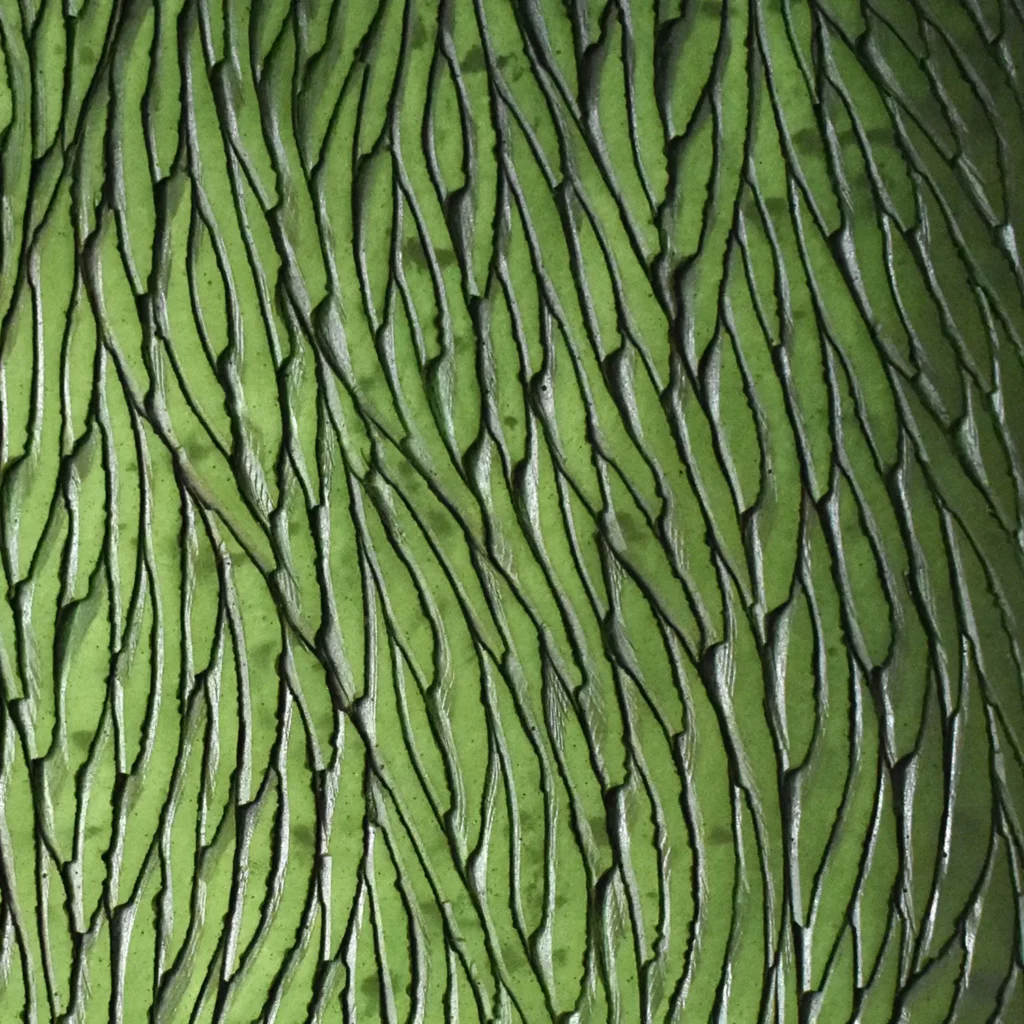 Un zoom immersif sur la matière sculptée par l'atelier Mylène Mai, ce sont des écailles de plâtre qui composent une œuvre murale contemporaine. Le relief est inspiré d'une organisation végétale ou organique. L'oeuvre est teintée de nuances de pigments verts clairs et foncés, travaillés en lavis et en dégradés doux et lumineux.