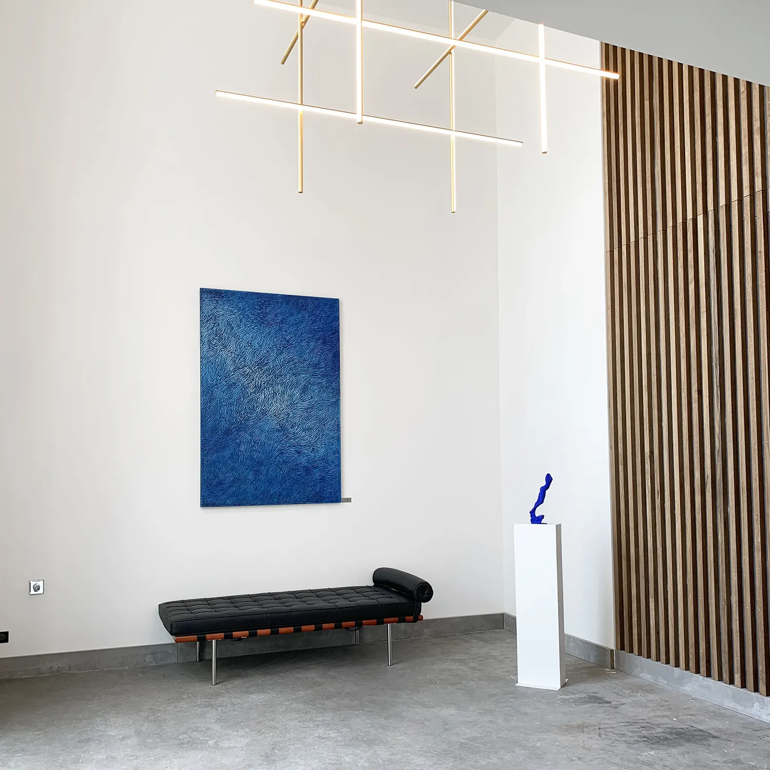 Hall d'accueil d'une entreprise lyonnaise, murs blancs, mobilier épuré, une sculpture murale de l'artiste Mylène Mai est installée.