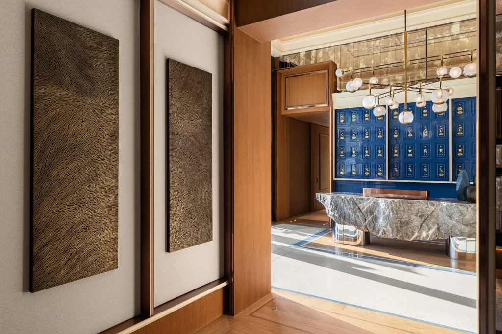 Vue du couloir de l'hôtel Marsa Al Arab desservant les restaurants gastronomiques. Au mur, une sculpture murale en triptyque de l'artiste Mylène Mai, en écailles de plâtre, aux teintes de bronze doré. Le lieu est luxueux et raffiné