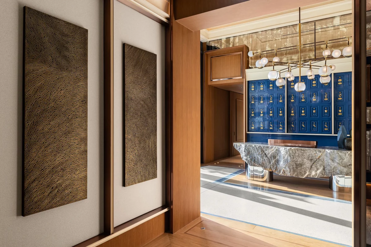 Vue du couloir de l'hôtel Marsa Al Arab desservant les restaurants gastronomiques. Au mur, une sculpture murale en triptyque de l'artiste Mylène Mai, en écailles de plâtre, aux teintes de bronze doré. Le lieu est luxueux et raffiné