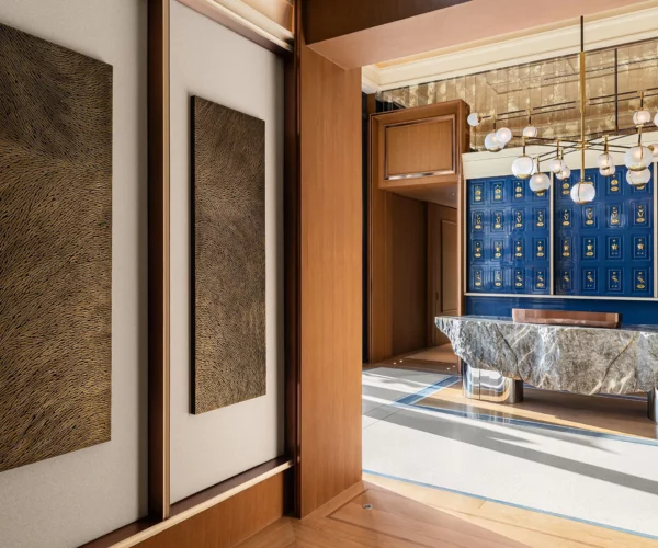 Vue du couloir de l'hôtel Marsa Al Arab desservant les restaurants gastronomiques. Au mur, une sculpture murale en triptyque de l'artiste Mylène Mai, en écailles de plâtre, aux teintes de bronze doré. Le lieu est luxueux et raffiné