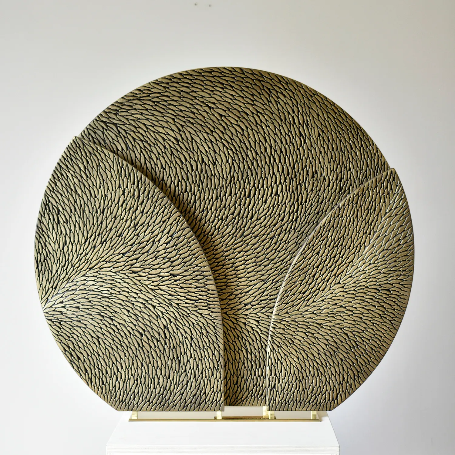 Une sculpture sur socle en laiton et petites écailles de plâtre bronze doré, de forme ronde, en 3 pièces pour apporter du volume. Le socle de la sculpture est en laiton poli miroir.