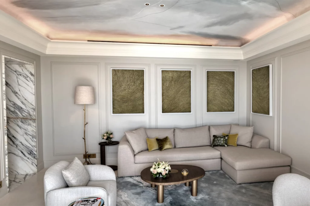 Dans le salon de la suite penthouse du grand hotel du cap, hôtel four seasons de saint jean cap ferrat, au mur, au dessus du canapé, un quadriptyque réalisé par l'atelier Mylène Mai est accroché. une oeuvre sur mesure, pièce unique, en écailles de plâtre et aux teintes bronze doré.