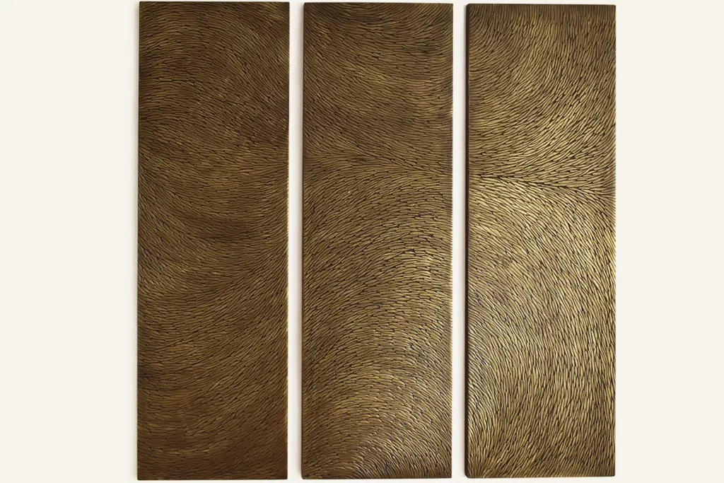 Un triptyque, oeuvre murale en écailles sculptées de plâtre, aux teintes de bronze et doré en surface