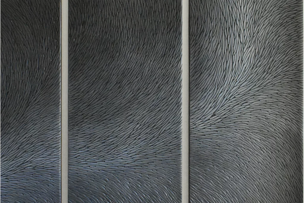 Vue en zoom d'une œuvre murale en triptyque, constituée d'écailles de plâtre sculptées. La patine est réalisée à partir e pigments noir et gris mat.