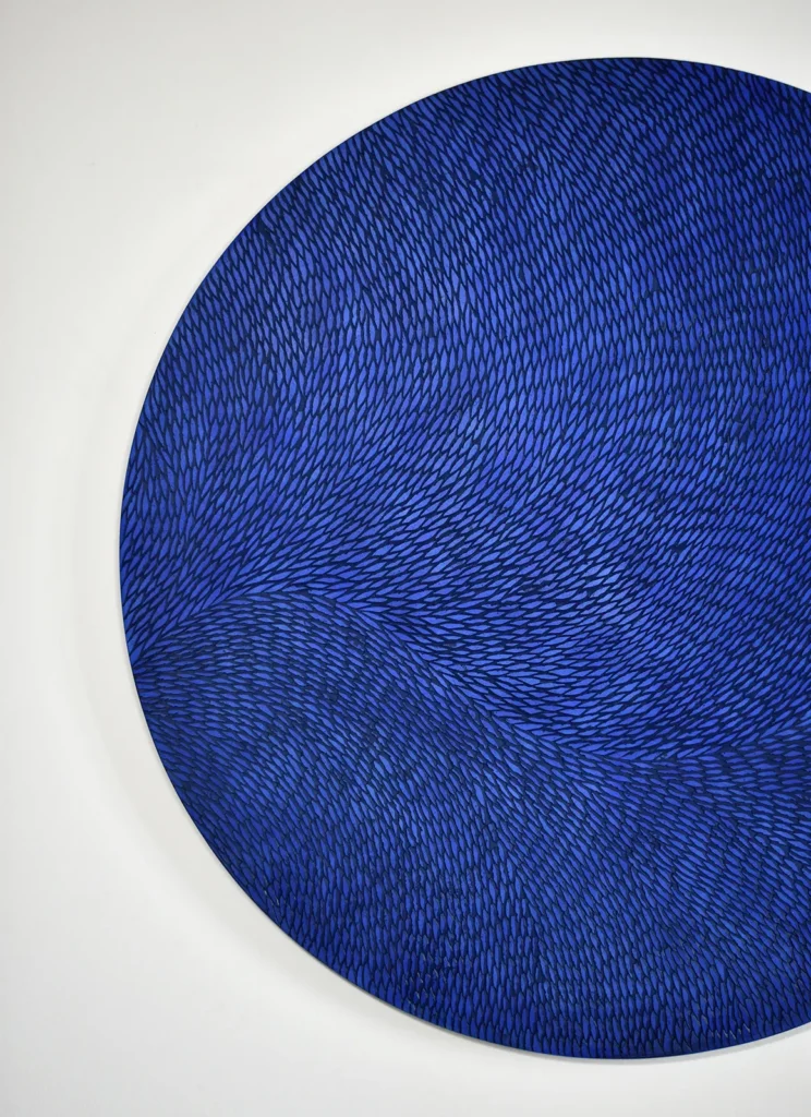 Vue de face partielle d'une oeuvre murale ronde. Cette pièce unique et sur mesure est une sculpture murale en plâtre, la patine est dans des teintes de bleu soutenu.