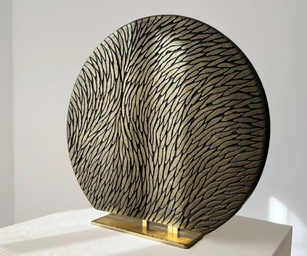 Vue de trois quart d'une sculpture à poser, sur socle, en plâtre et laiton. Une oeuvre en relief, constituée d'écailles de plâtre sculptées, aux couleurs bronze et doré. Un objet d'art luxueux et raffiné.