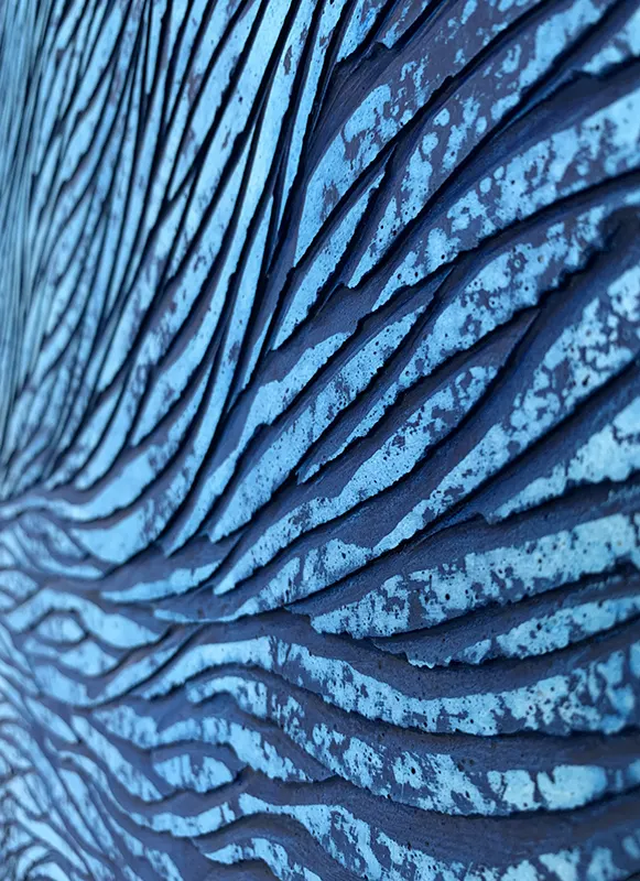 Zoom sur une oeuvre en écaille de plâtre sculptées par l'artiste Mylène Mai. Les teintes sont en dégradées de bleus.