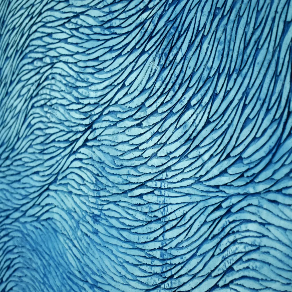 Zoom sur la patine aux tons de bleus doux et azur de cette sculpture murale sur mesure.