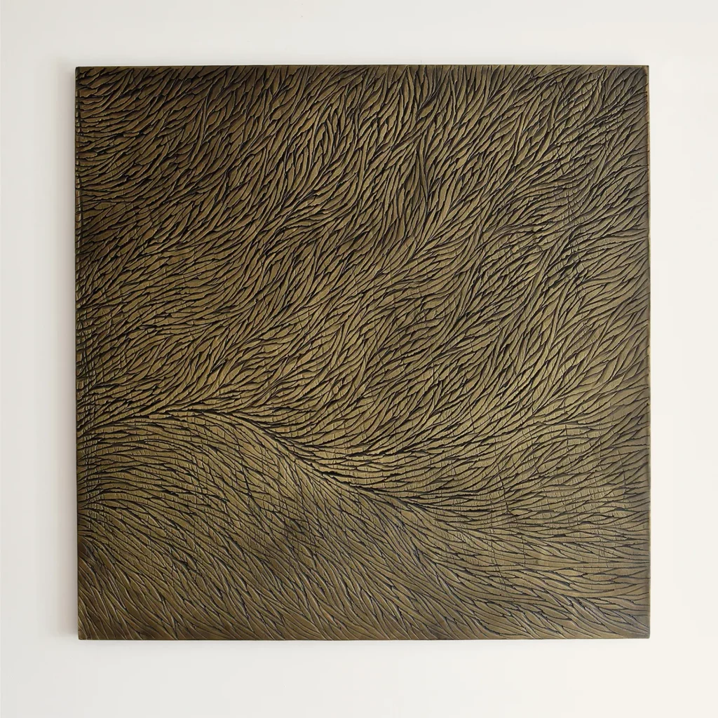 Sculpture murale de l'atelier Mylène Mai, accrochée sur un mur blanc type galerie, l'oeuvre est en platre sculptée, constituée de multiples écailles, la teinte de l'oeuvre est dans des nuances de bronze et de doré. Le relief de cette oeuvre contemporaine capte la lumière.