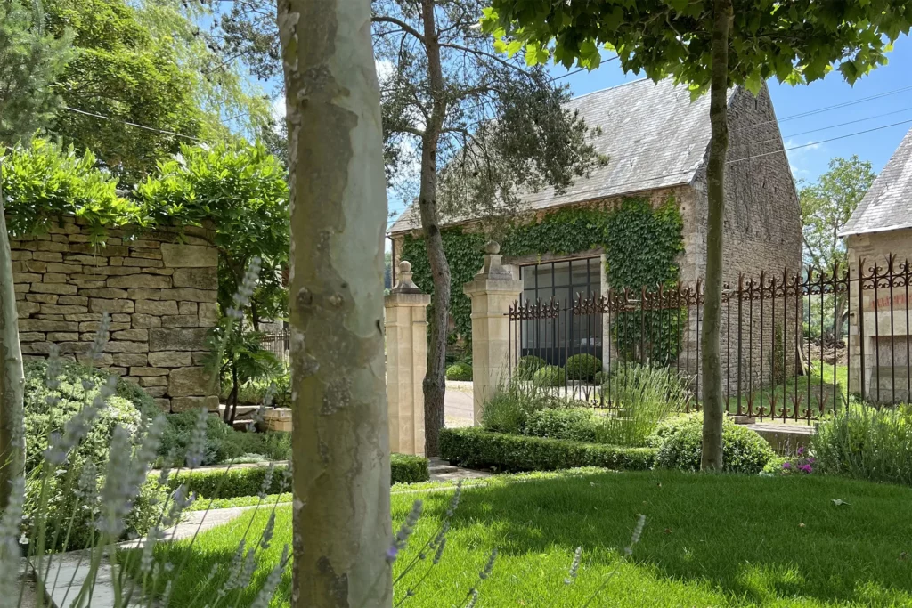 la façade l'atelier Mylène Mai, on aperçoit la grande verrière de l'entrée, vue depuis un jardin de caractère en Bourgogne