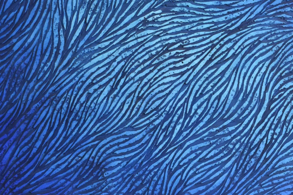 Un détail sur les écailles de plâtre d'une sculpture murale de l'artiste Mylène Mai. Une patine aux nuances de bleus avec des pigments différents et des dégradés doux et lumineux.